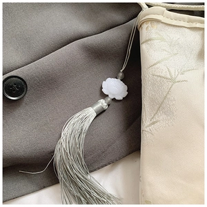Close-up of white lotus bead and silky tassel on a Chinese style jacquard bag