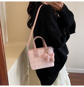 Pink checkered crossbody bag with cute puppy charm and logo detail on black outfit