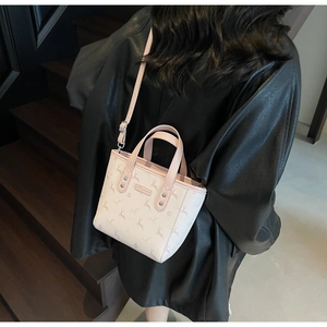 Rear view of a light beige printed bucket bag with deer patterns and leather straps