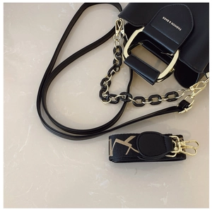 Detail of black bucket bag with gold horseshoe handle and interchangeable geometric straps