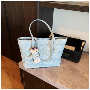 Detail of light blue woven tote bag with bubble texture and cute teddy bear charm