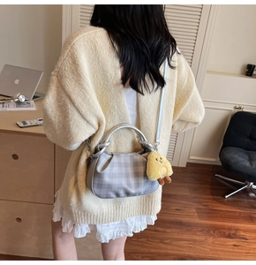 Detail of grey plaid pleated cloud bag with silver handle and yellow chick charm