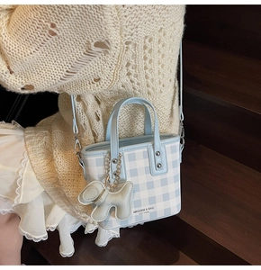Dettaglio della borsa tote a quadretti blu con ciondolo a cucciolo e tracolla regolabile