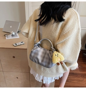Silver checkered hobo bag with ring handles and a yellow chick plush charm on model