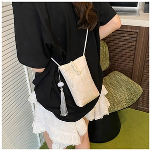 Detail of embroidered bamboo and floral patterns on an elegant crossbody phone bag
