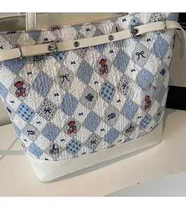 Detail of white bubble quilted tote bag with blue bear prints and metal buckle strap