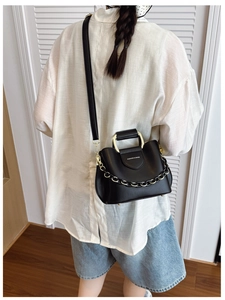 Detail of black bucket bag featuring gold metal handle and FASHION & BAGS lettering