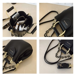 Detail of black structured bag with gold metal handle and artistic print wide strap