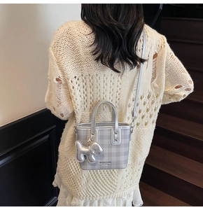 Close-up of silver-gray plaid crossbody bag featuring a cute metallic puppy charm