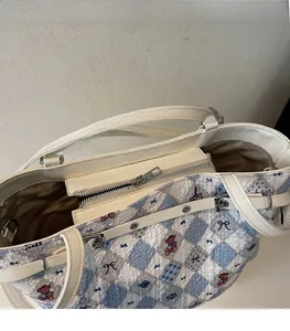 Detail of smooth silver zipper and interior lining on a blue plaid teddy bear tote bag