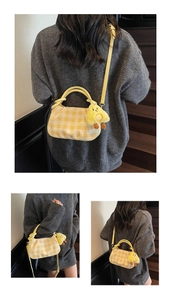 Detail of yellow checkered crossbody bag with a cute plush chick pendant on wooden stairs