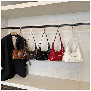 Cinq sacs sous le bras colorés avec boucles en croissant dorées sur présentoir sobre