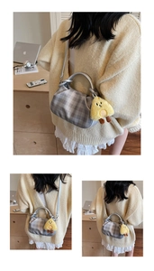 Detail of grey checkered pleated handbag with silver handle and yellow chick charm