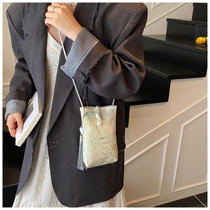 Detail of elegant Chinese style mini crossbody bag with bamboo leaf pattern and tassel
