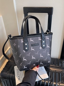 Fashionable black printed bucket bag with deer motifs placed on a suitcase for travel