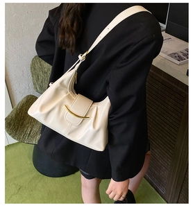 Détail du sac à bandoulière beige en cuir brillant avec boucle dorée et plis chic