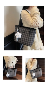 Detailed close-up of checkerboard tote bag with black leather straps and cloud plush charm