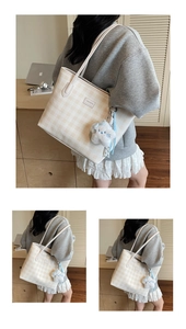 Detail shot of a large beige checkerboard tote bag with a plush charm and brand logo