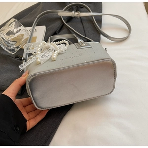 Vue détaillée d'un sac seau argenté avec dentelle élégante et breloques en perles