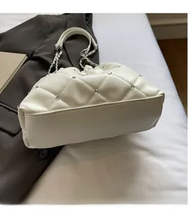 Détail du sac beige matelassé avec strass argentés et bandoulière en chaîne
