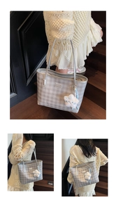 Detail of silver checkerboard tote bag with metallic logo and plush white charm