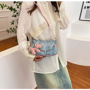Close-up of blue denim textured crossbody bag with sequin detail and pink puppy charm