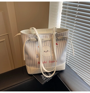 Detail of striped canvas tote bag featuring a cute seal print and white leather handles