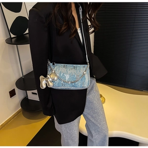 Detail of sequined denim underarm bag with silver chain and metallic charm