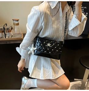 Detail of black quilted shoulder bag featuring silver star studs and hanging charm
