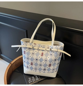 Macro detail of blue and white quilted embroidery featuring bears and bow patterns on a tote bag