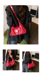 Détail du sac bandoulière en cuir verni rouge avec boucle dorée et texture plissée