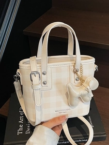 Cream checkered bucket bag with dual handles and cute puppy charm on vintage book