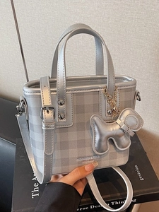 Silver-gray plaid handbag with top handles and a cute dog charm in a lifestyle shot