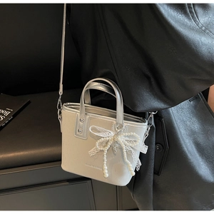 Detailed shot of silver handbag with pearl bow, lace accents and fashion lettering
