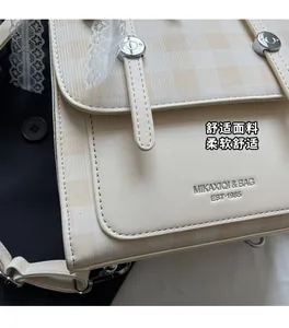 Close-up of vintage beige plaid crossbody bag with lace trim and metal buckle detail
