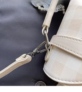 Detailed macro view of silver lobster clasp and beige plaid texture on student backpack
