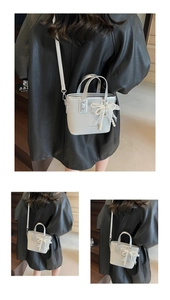 Detail of silver bucket bag with lace pearl bow and metallic heart pendant