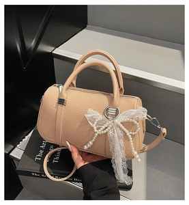 Dettaglio della borsa in pelle beige con decorazione di perle e fiocco in pizzo