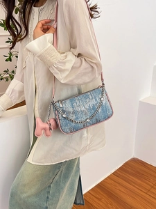 Blue sequin underarm bag with pink strap, metal chain and puppy pendant on model
