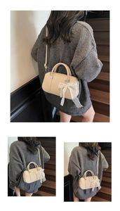 Dettaglio borsa beige con trama litchi, fiocco in pizzo di perle e tracolla