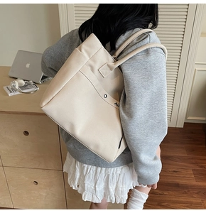 Detail of a large off-white canvas tote bag with AIR logo shown on a person's shoulder