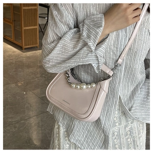 Detail of light pink shoulder bag featuring matte leather and a large pearl chain strap