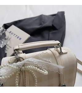 Detail of cream plaid handbag featuring pearl handle strap and lace bow decoration
