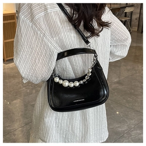 Détail du sac demi-lune noir avec perles blanches décoratives et chaîne en métal argenté