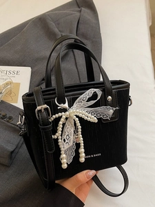 Sac seau noir chic avec charm nœud en perles et bandoulière réglable sur blazer