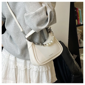 Détail du sac demi-lune blanc crème avec bandoulière de perles élégante et logo en métal