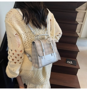 Detail of grey plaid backpack with vintage rebel text and pearl lace bow accessory