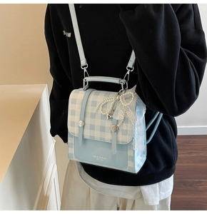 Detail of blue plaid mini backpack with lace bow and pearl heart pendant charm