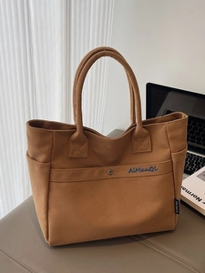 Brown canvas tote bag with metal snap pocket and dual handles for daily commute