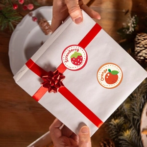 Rotolo di adesivi di fragole e arance su una scatola regalo per decorazione